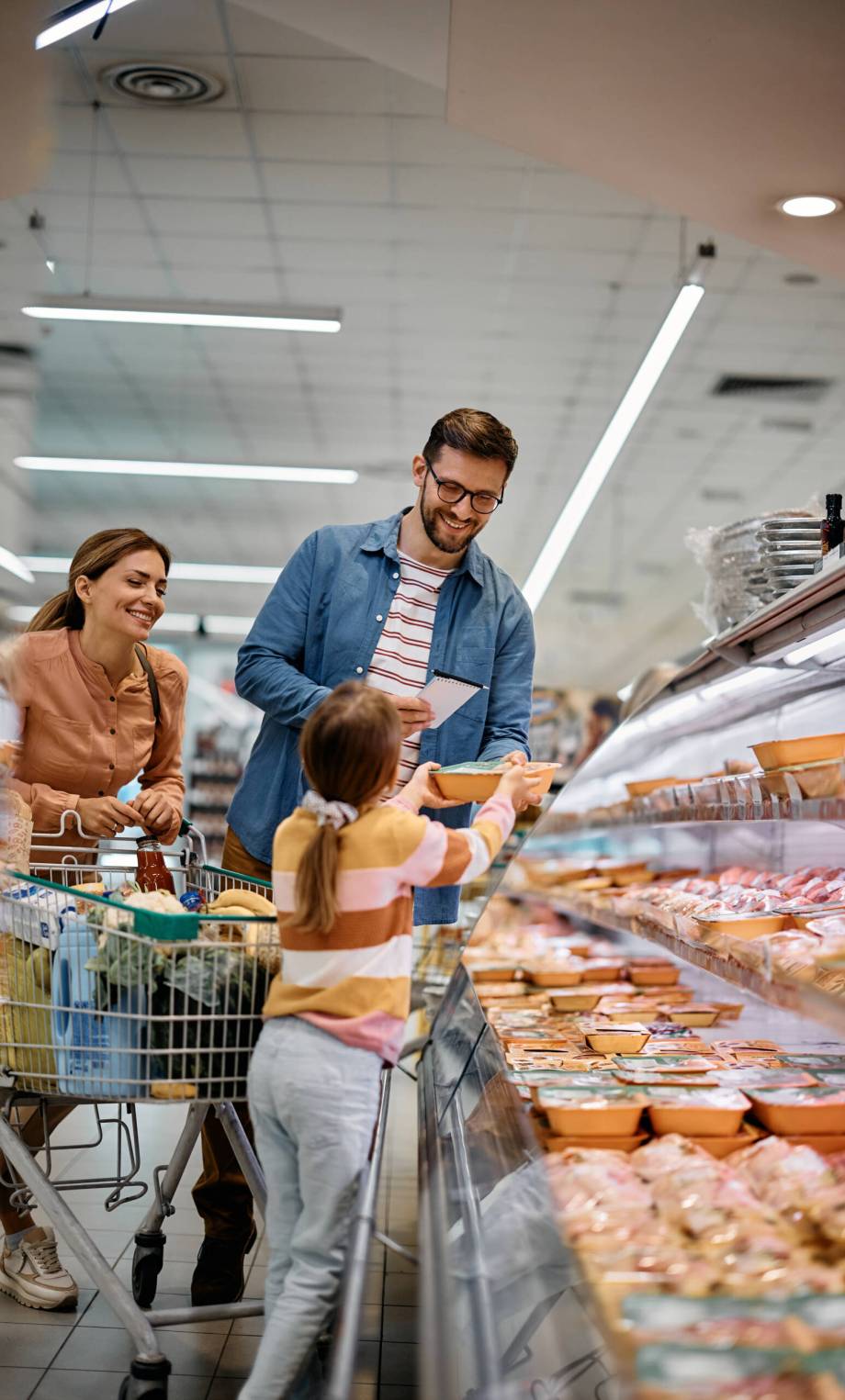 Little girl and her parents shopping food in the supermarket.